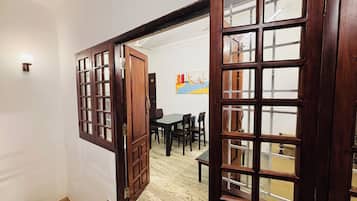 A room with a wooden door leading to a dining area with a table and chairs.