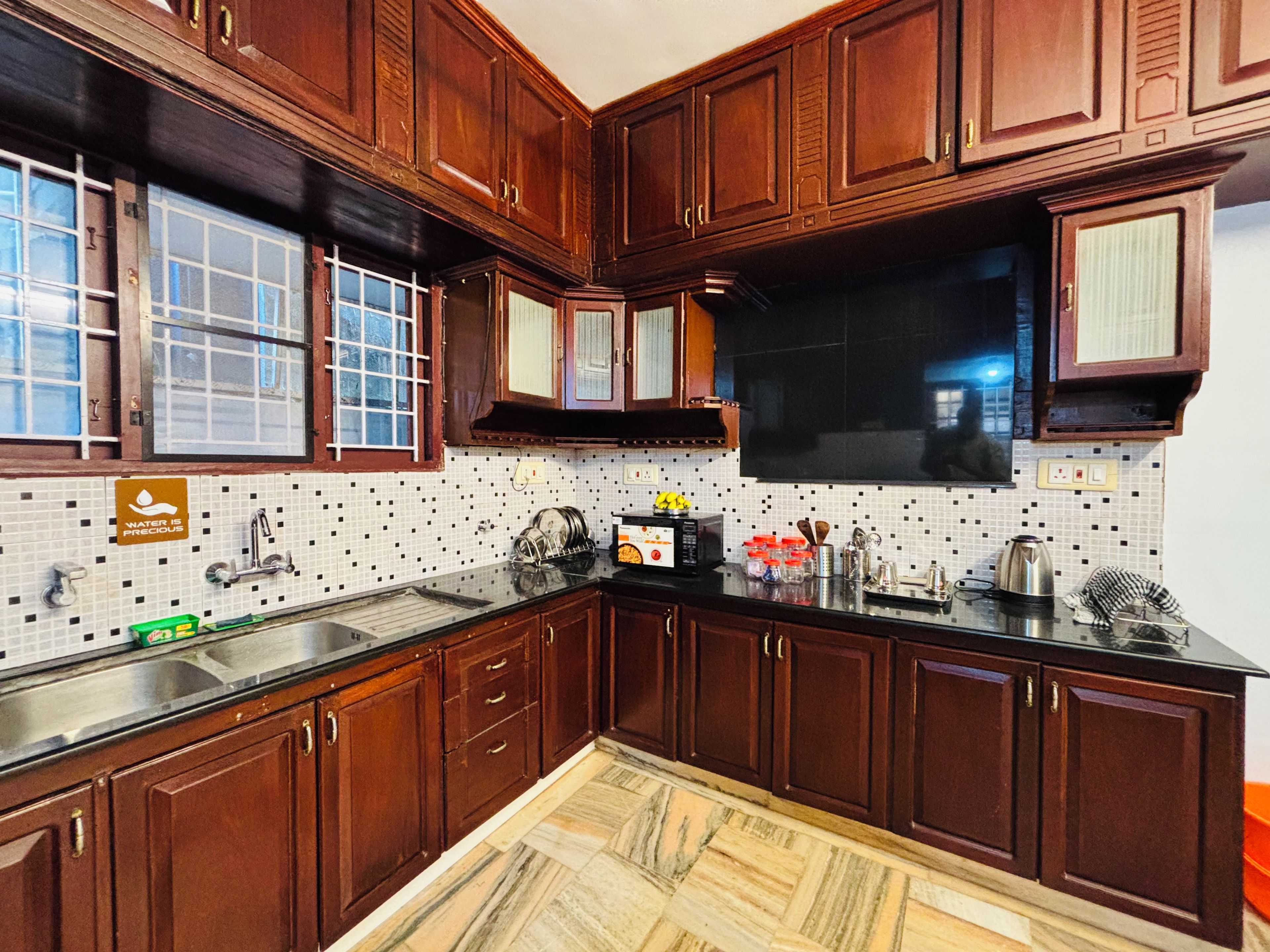 A kitchen with wooden cabinets, a tiled backsplash, and a stainless steel sink.