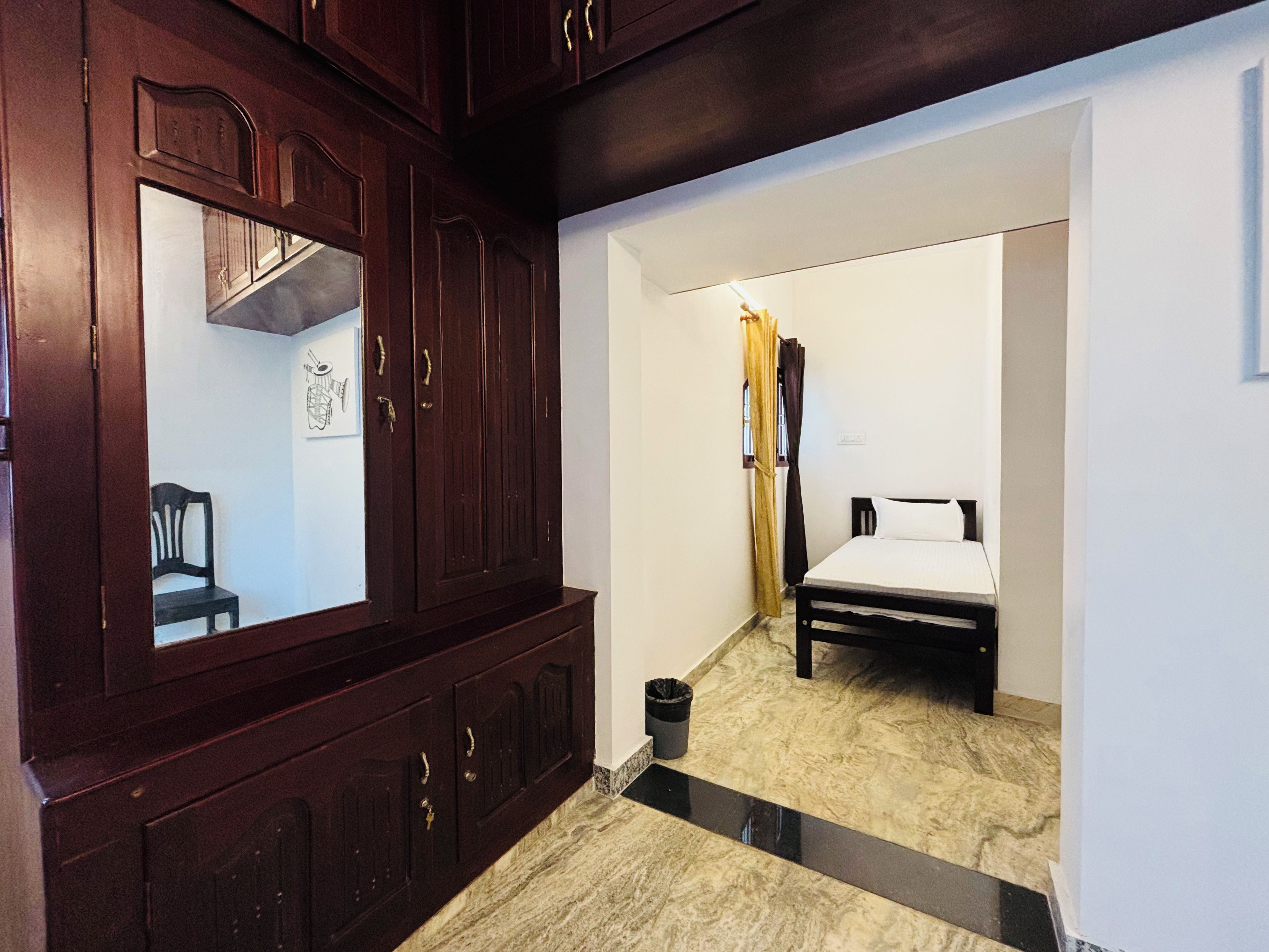 A room with a bed, a wardrobe, and a small chair.
