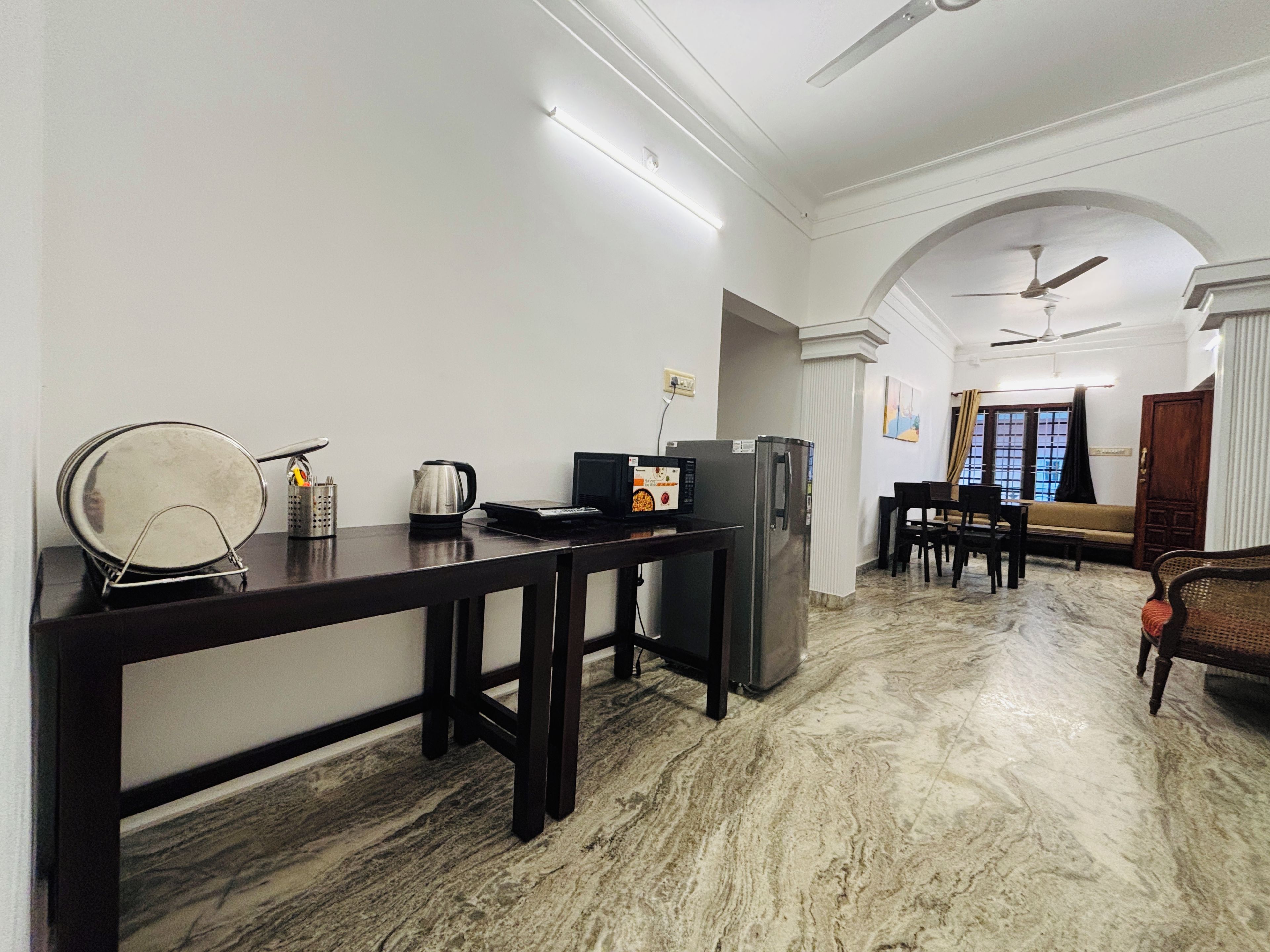A modern living room with a dark wooden table, a refrigerator, and a sofa.