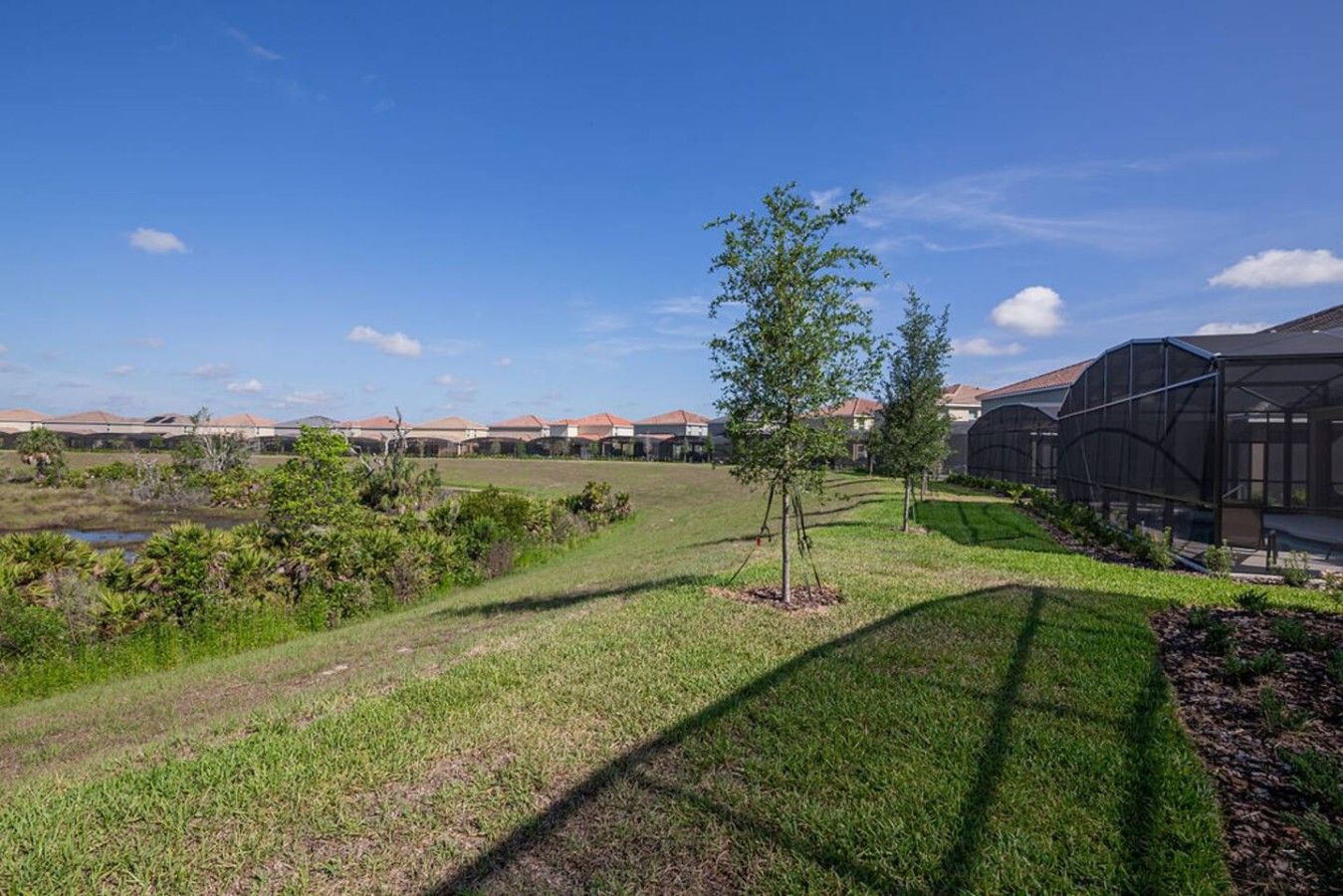 A residential area with houses, a grassy field, and a greenhouse structure.
