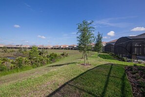 A residential area with houses, a grassy field, and a greenhouse structure. - 5BR Pool Home | Mickey & Star Wars Rooms (Davenport)