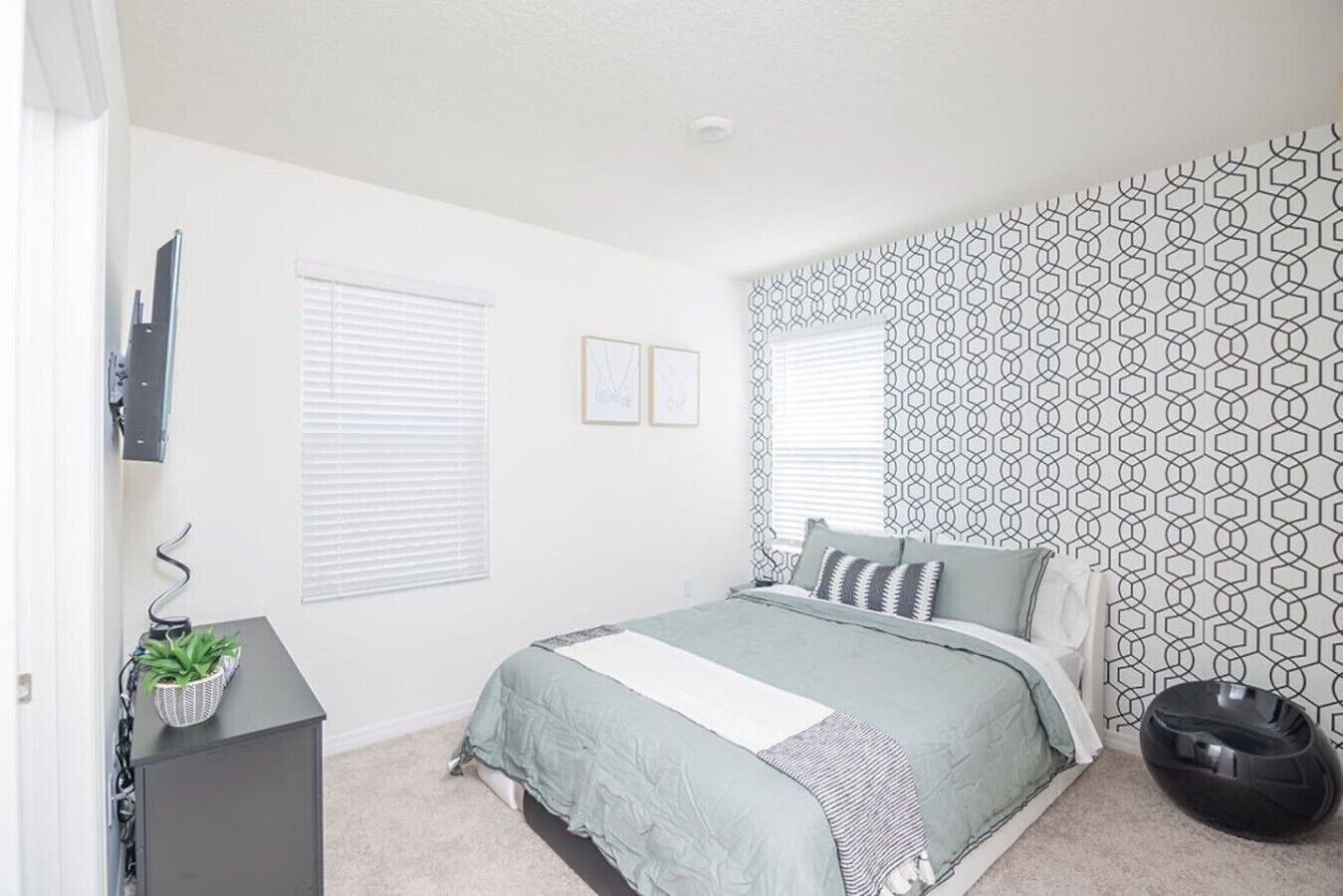 A bedroom with a bed, a desk, a chair, and a potted plant.