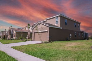 A residential building with a garage, a driveway, and a well-maintained lawn. - 5BR Pool Home | Mickey & Star Wars Rooms (Davenport)
