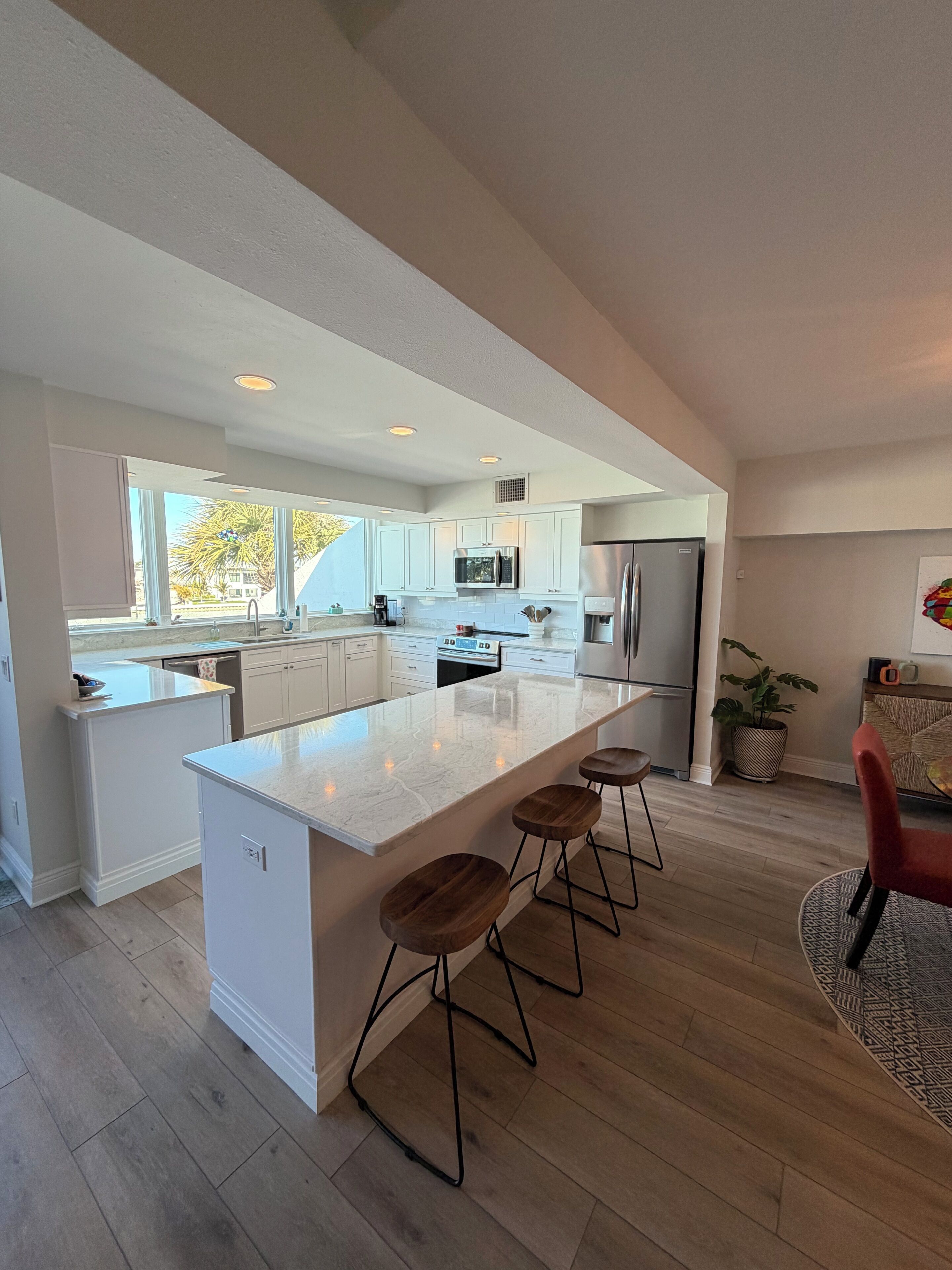 A modern kitchen with a large island, bar stools, and stainless steel appliances.