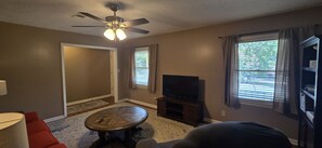 Ein Wohnzimmer mit Deckenventilator, Flachbildfernseher, Couchtisch und Sofa.