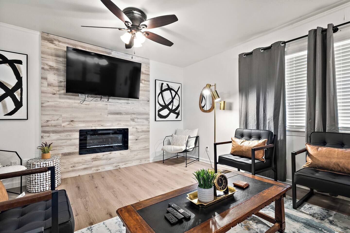 Ein modernes Wohnzimmer mit Flachbildfernseher, Kamin, Deckenventilator und Sitzgruppe.