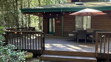 Eine Hütte mit einer Terrasse, Sitzgelegenheiten im Freien und einer überdachten Veranda.