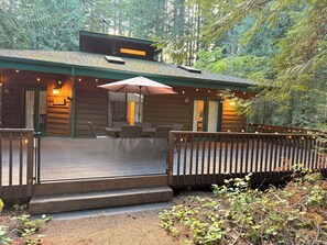 A wooden cabin with a deck, outdoor seating, and a covered patio area. - Serene Family Friendly Cabin, Walk to Lake Cushman, Cozy Wood Stove & Gated Deck (Hoodsport)