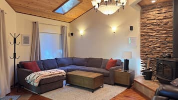 Ein modernes Wohnzimmer mit einer Eckcouch, einem Kamin und einer Wand mit Steinverkleidung.