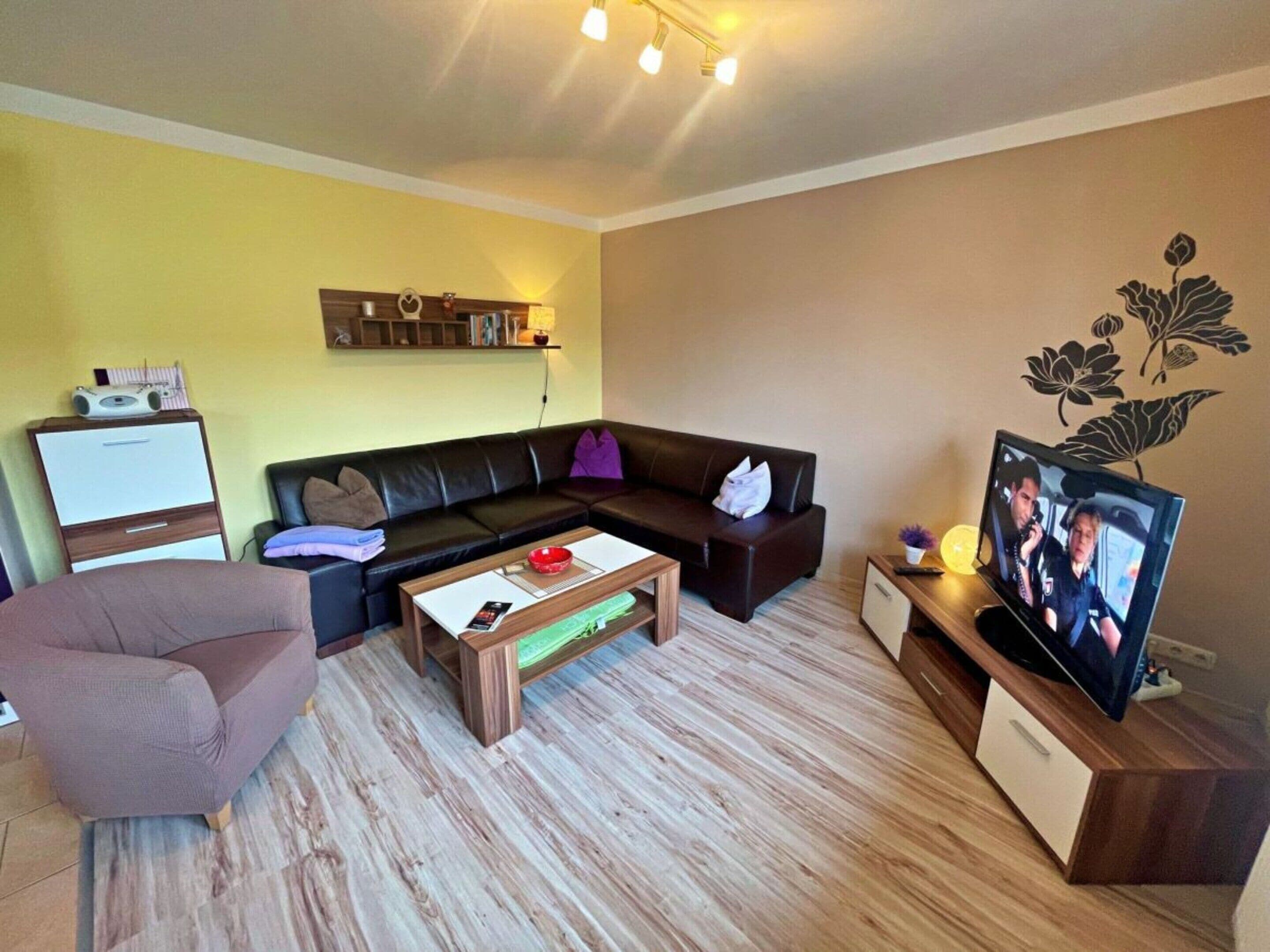 Ein Wohnzimmer mit einer Couch, einem Couchtisch, einem Fernseher und einem Schrank.