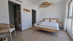 Ein Schlafzimmer mit Bett, Stuhl, Kleiderschrank und Fenster.