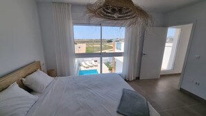Ein Schlafzimmer mit Bett, Fenster und Blick auf einen Swimmingpool.