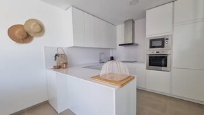 Eine moderne Küche mit weißen Schränken, einem eingebauten Backofen und einer Mikrowelle.