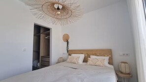Ein Schlafzimmer mit Bett, Kleiderschrank, Pendelleuchte und Nachttisch.