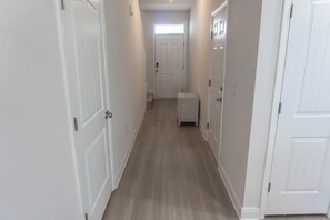 Ein schmaler Flur mit weißen Türen an beiden Seiten, einem kleinen weißen Schrank in der Mitte und einem Lichtschalter an der Wand.
