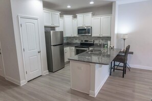 A modern kitchen with white cabinets, stainless steel appliances, and a granite countertop. - Pet-Friendly Lake Views from Most Rooms, Townhome, Walk to Beach & (Panama City)