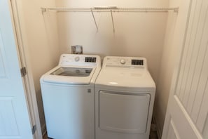 Une buanderie équipée de deux machines à laver à chargement frontal, de couleur blanche, et d’un étendoir placé au-dessus.
