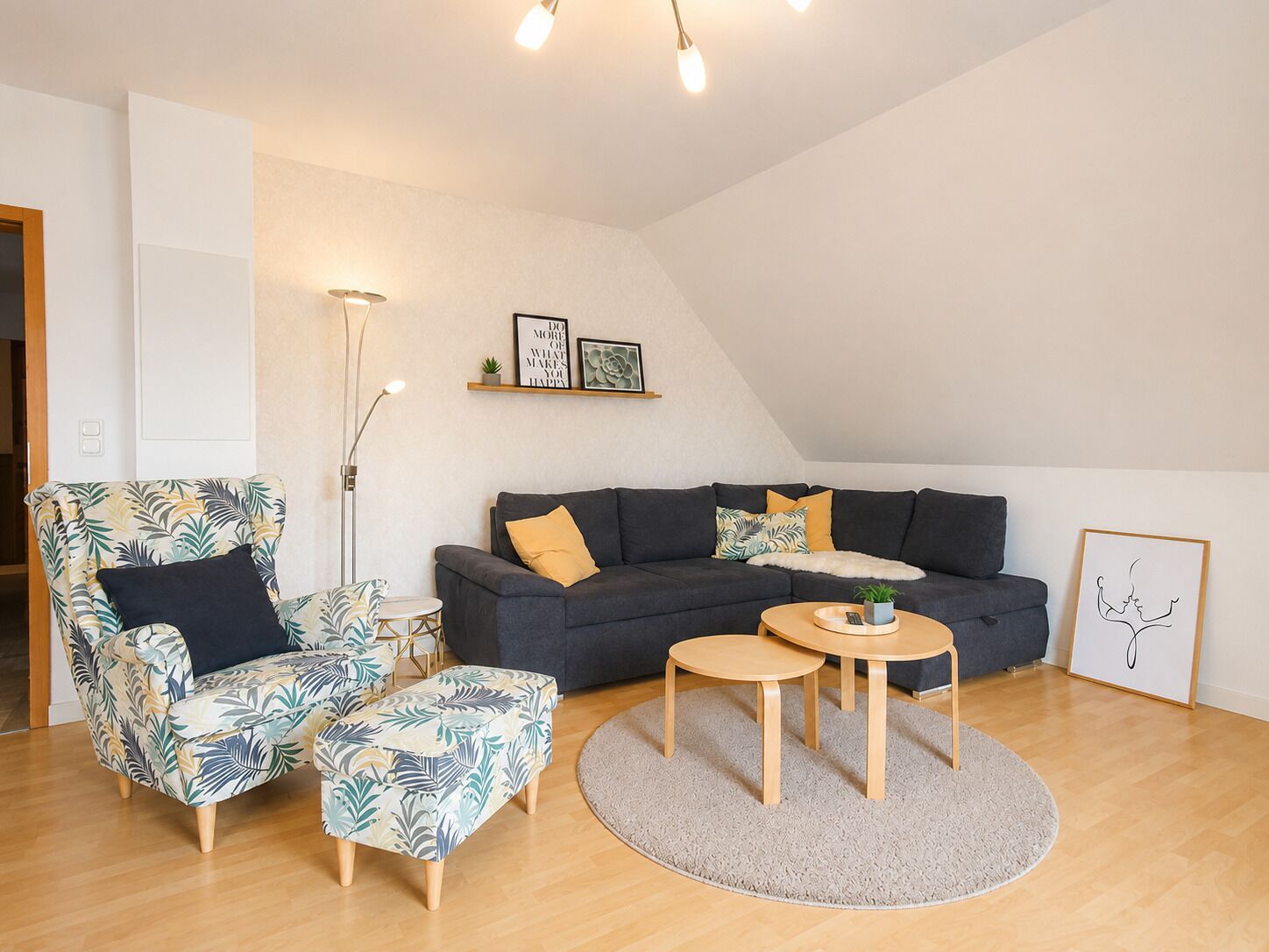 Ein stilvolles Wohnzimmer mit Sofa, Sessel und Couchtisch, ausgestattet mit einem großen Fenster und hoher Decke.