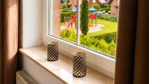 A window with a view of a residential area, including houses and a playground. - Meerbeck Vacation Rental (Meerbeck)