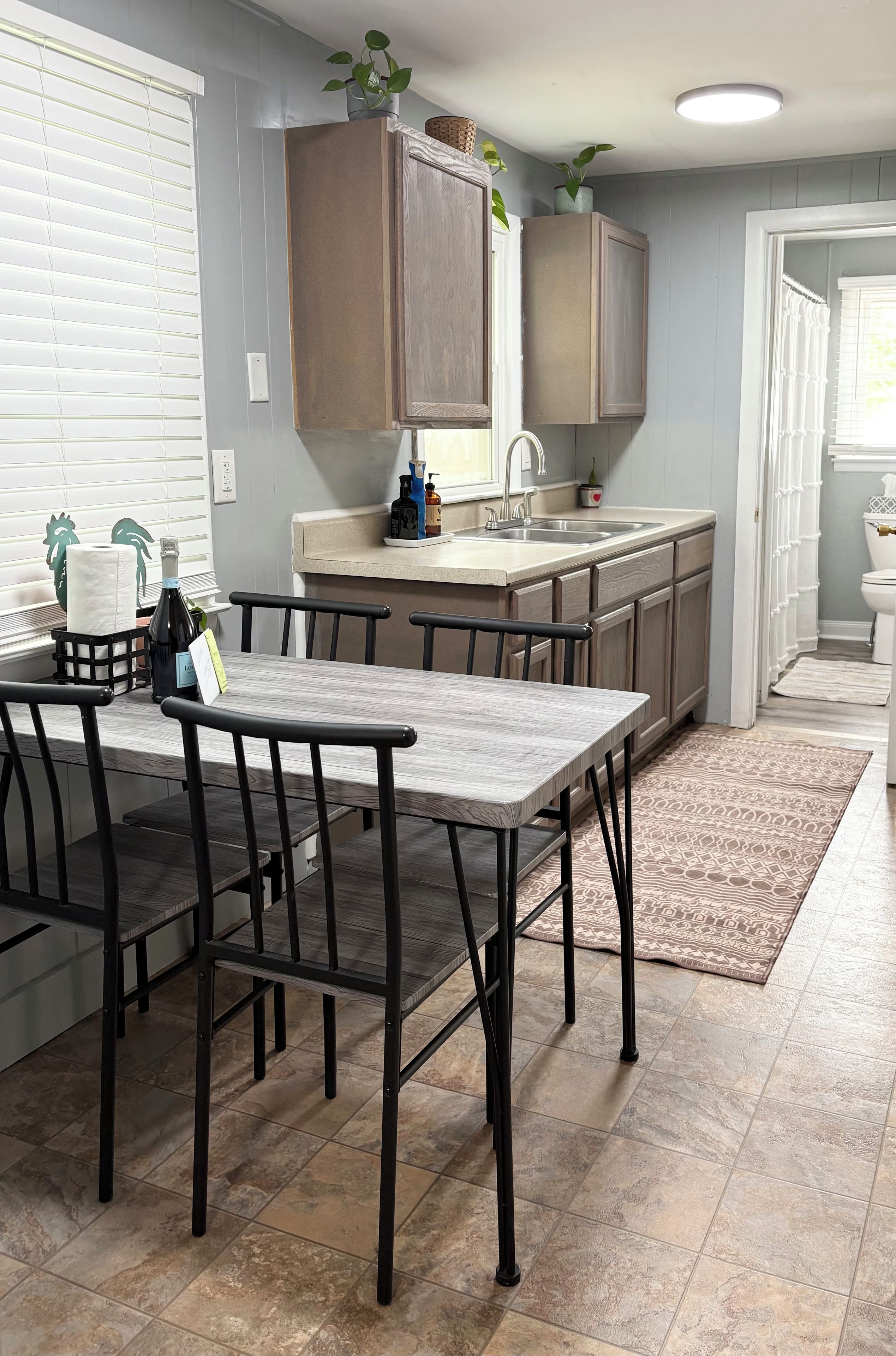 A kitchen with a dining table and chairs, a sink, and cabinets.