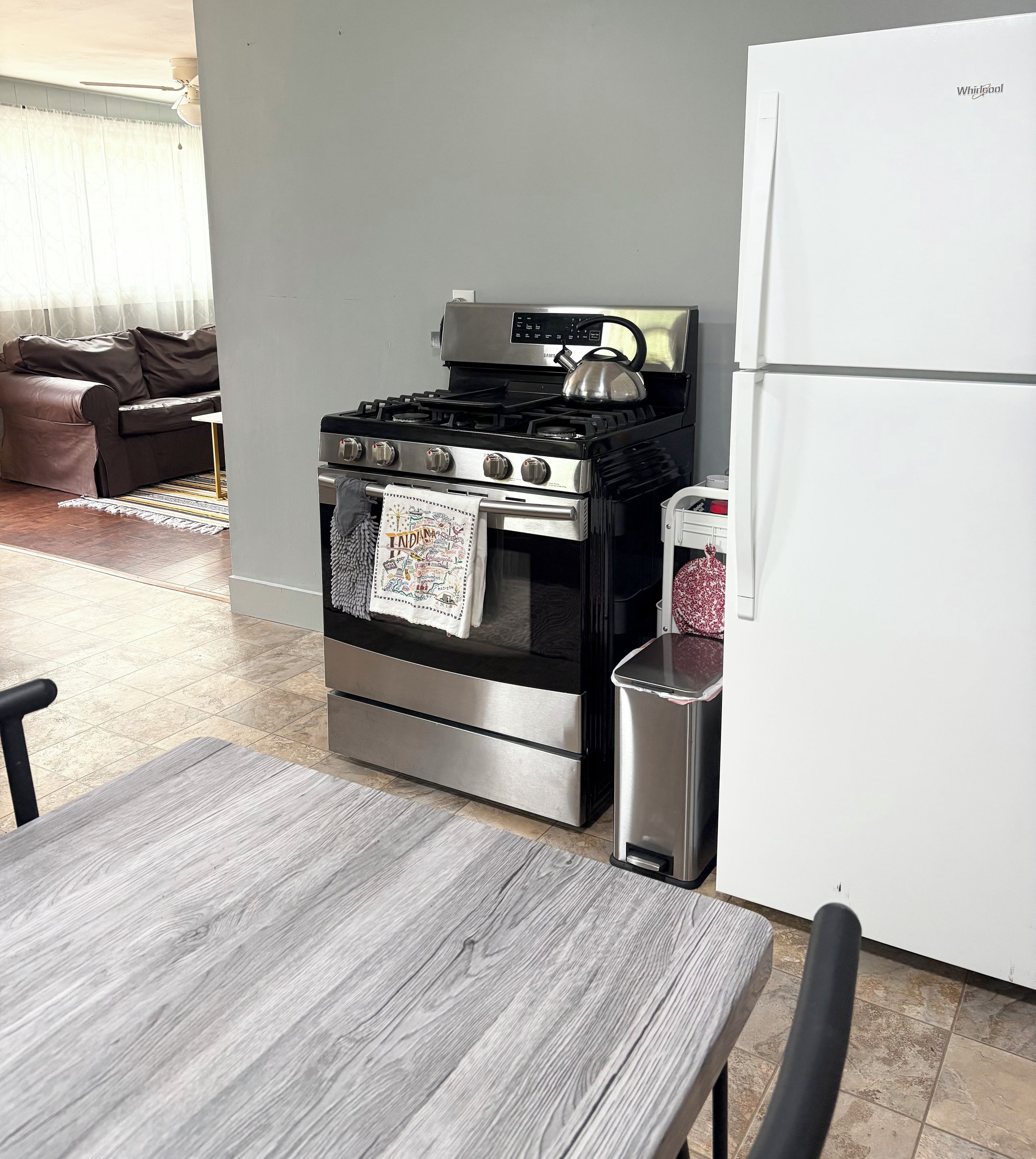 Una cocina con estufa de acero inoxidable, un refrigerador y una mesa de comedor.