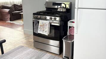 Una cocina con estufa de acero inoxidable, un refrigerador y una mesa de comedor.