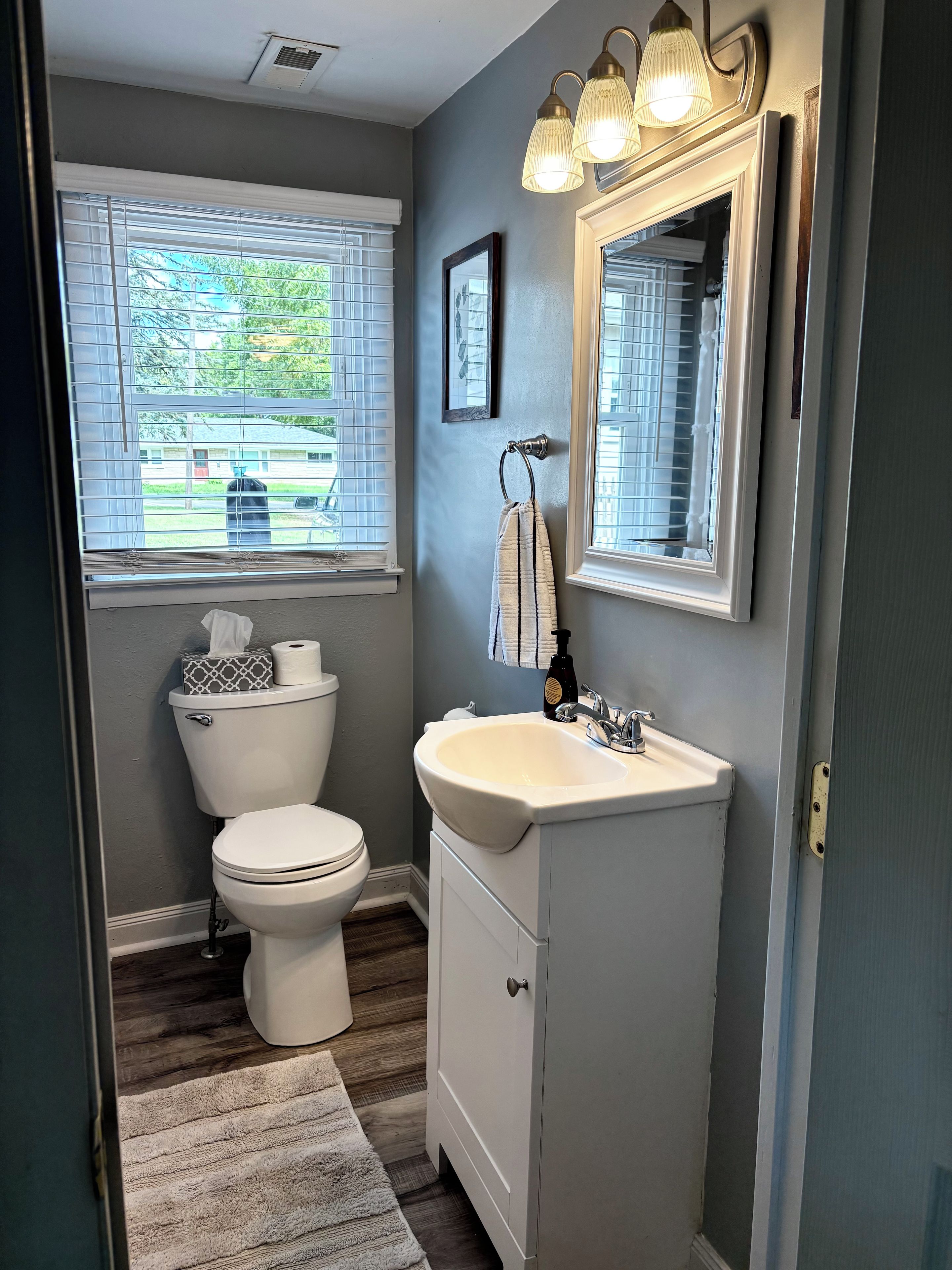 A bathroom with a toilet, sink, and window.