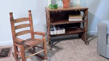 Una mecedora de madera y una mesita auxiliar con libros y una planta en maceta.