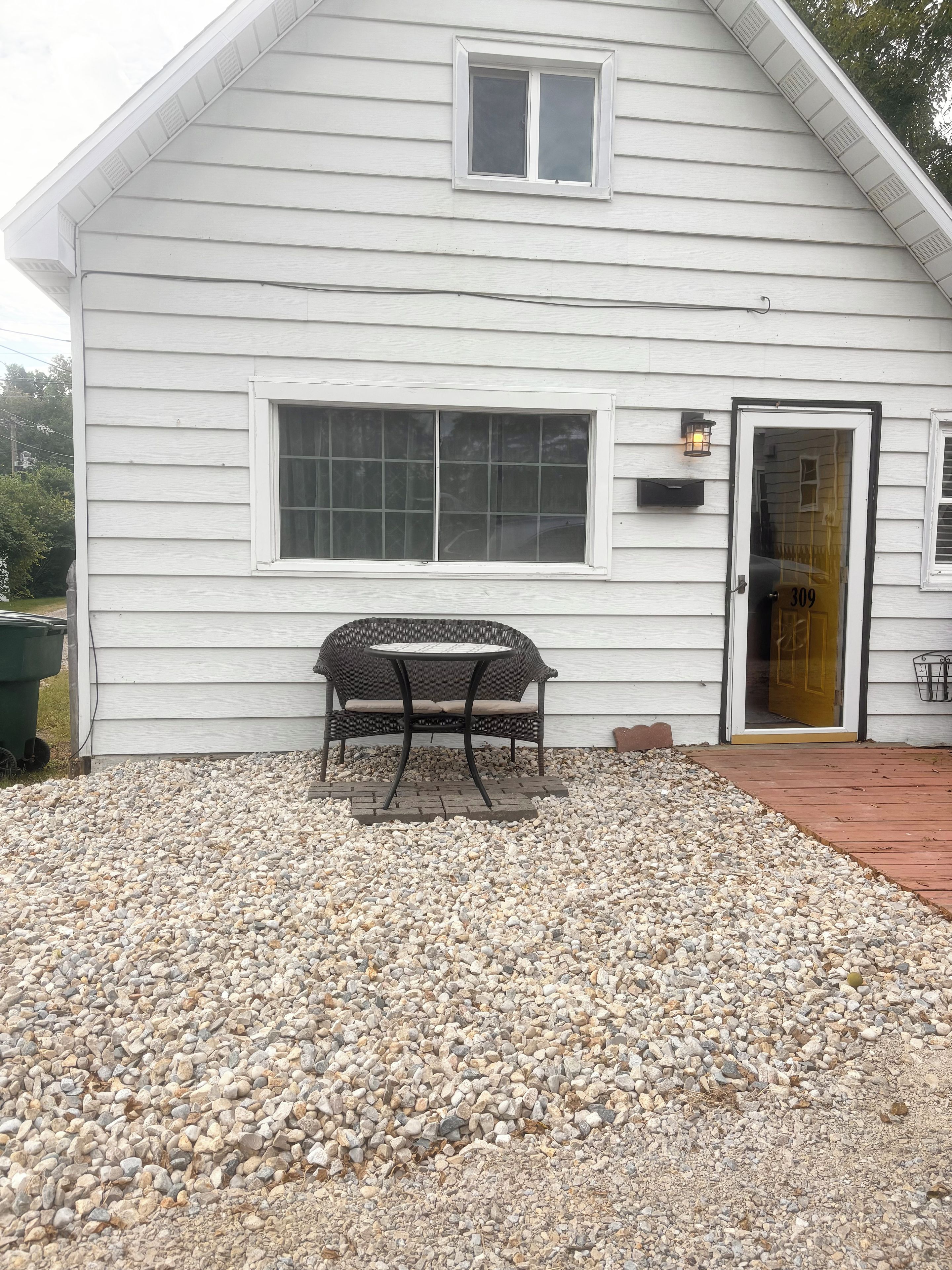A house with a gravel driveway, a patio table, and a door with the number 309.