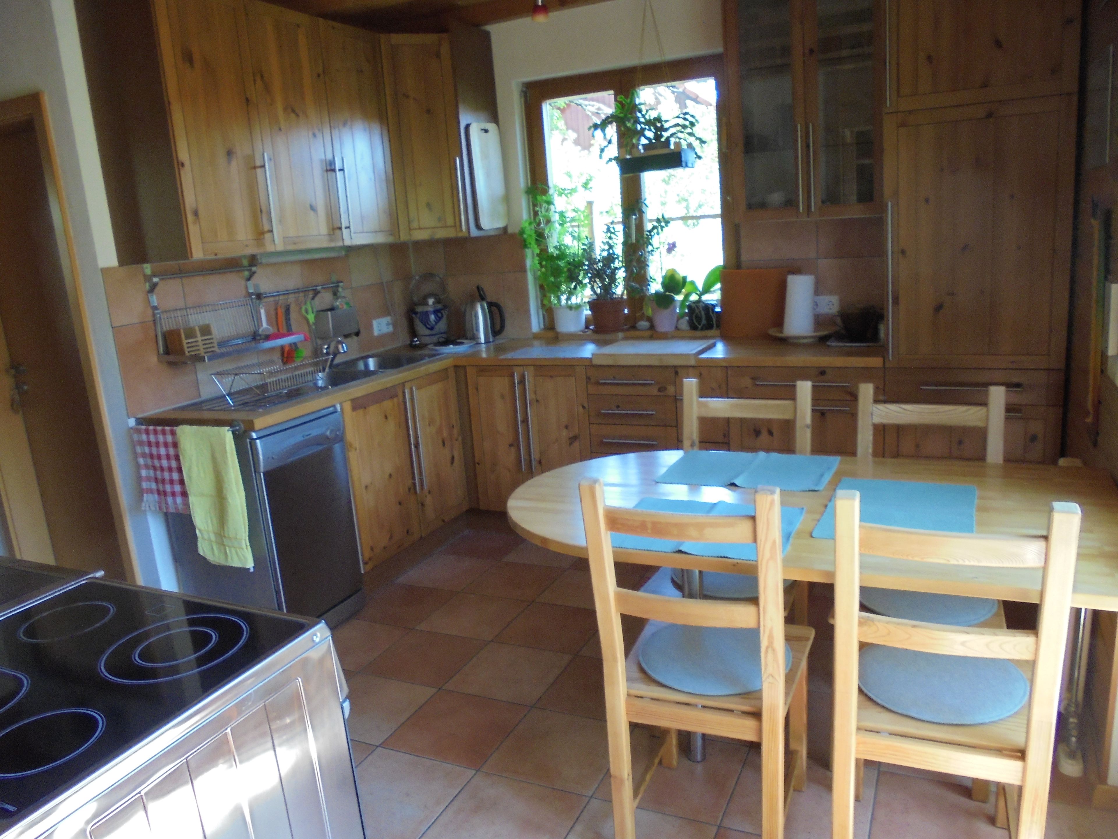 A kitchen with wooden cabinets, a stove, and a dining table with chairs.
