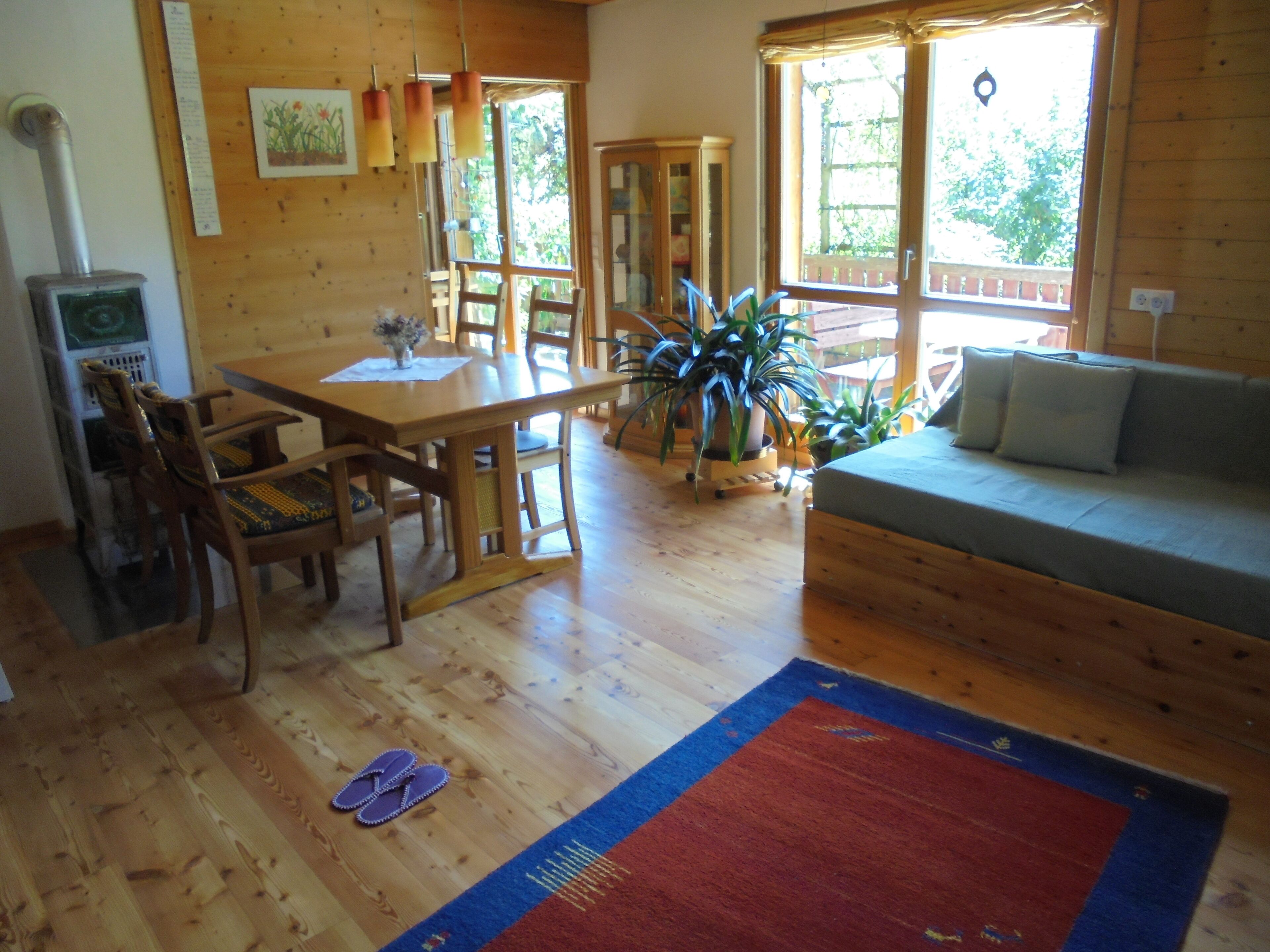 Un intérieur en bois comprenant une table à manger, des chaises, un canapé et une grande fenêtre.