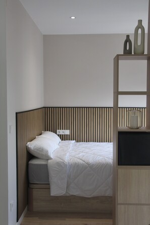 A bedroom with a bed, a bedside table, a nightstand, a wall-mounted shelf, and a ceiling light. - DULCE ESTRELA APARTMENTS: 5 minutes from downtown, spectacular views (Tui)