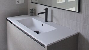 A bathroom with a white sink, a black faucet, and a large mirror. - Vrbo Property (Tui)