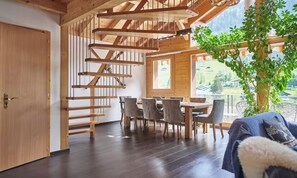 A wooden interior with a dining area, staircase, and a view of the outdoors. - TRADITIONAL SWISS CHALET WITH PANORAMIC LAUTERBRUNNEN VIEWS (Lauterbrunnen)