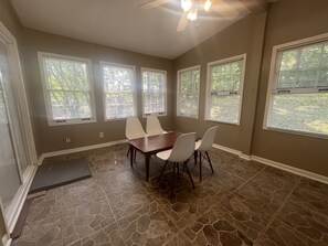 A dining area with a stone floor, a ceiling fan, and large windows with blinds. - Charming 3-bedroom house with AC in Buford (Buford)