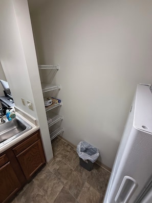 A kitchen with a sink, cabinets, a countertop, a refrigerator, and a trash bin. - Furnished 1BR Near OSU Reserved Parking + In-Unit Laundry (Columbus)