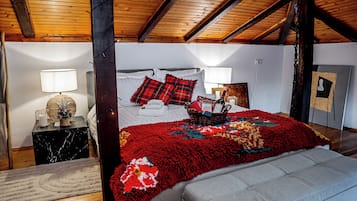 Une chambre avec un grand lit, un plafond en bois et une table de chevet avec une lampe.