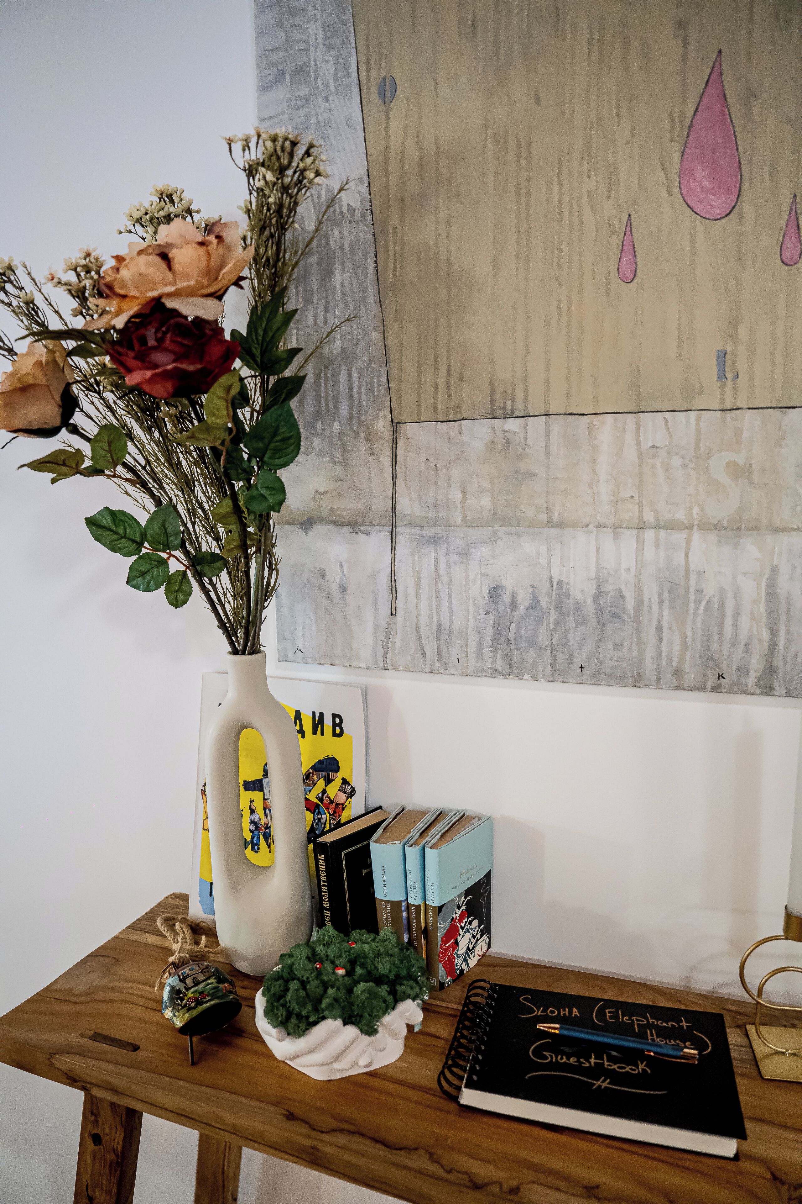 Une table en bois sur laquelle se trouvent un vase de fleurs, des livres et un carnet.
