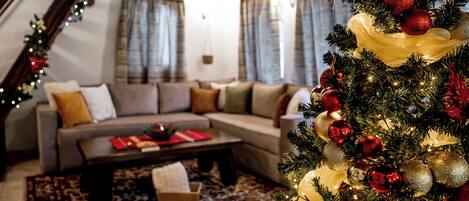Un salon chaleureux avec un canapé d’angle, une table basse et un sapin de Noël décoré.