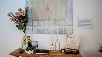 A wooden table with a vase of flowers, a notebook, a remote control, and a candle.
