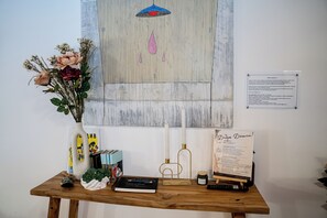 A wooden table with a vase of flowers, a notebook, a remote control, and a candle.