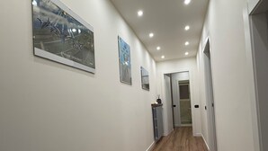 A hallway with wooden flooring, white walls, and recessed ceiling lights.