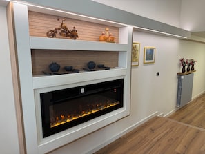 A modern fireplace with a built-in shelf above it, displaying decorative items.