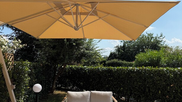 An outdoor seating area with a large canopy, cushioned chairs, and a small table.