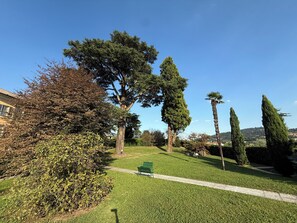 A park with a green bench, trees, and a clear sky. - Relais Pietro Luxury Apartment (Barzago)