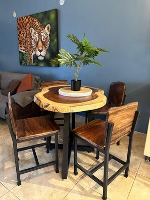 A round wooden table with a black metal frame, surrounded by four wooden chairs with metal legs. A potted plant is on the table. - Poolside 2-Bedroom Retreat | Walking Distance to Coco Beach (Guanacaste Province)