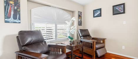 A living room with two leather armchairs, a wooden coffee table, and a window with white blinds.