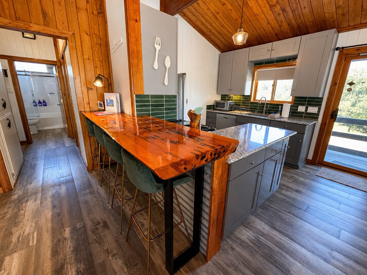 Een moderne keuken met een houten kookeiland, barstoelen en uitzicht op de omgeving.