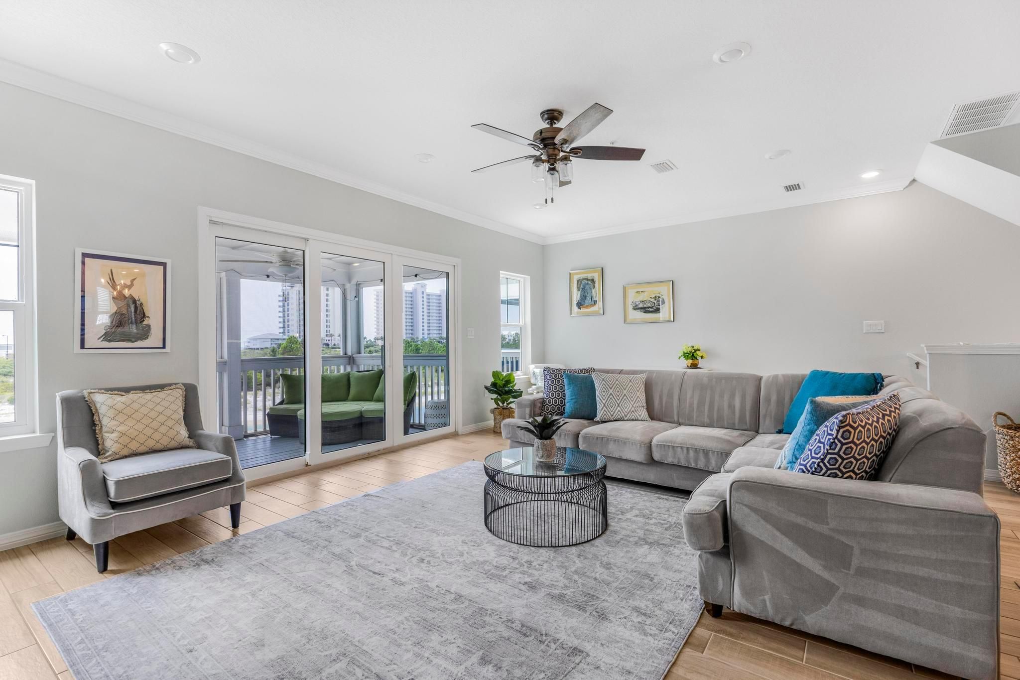 A modern living room with a grey sofa, a round coffee table, and a ceiling fan.